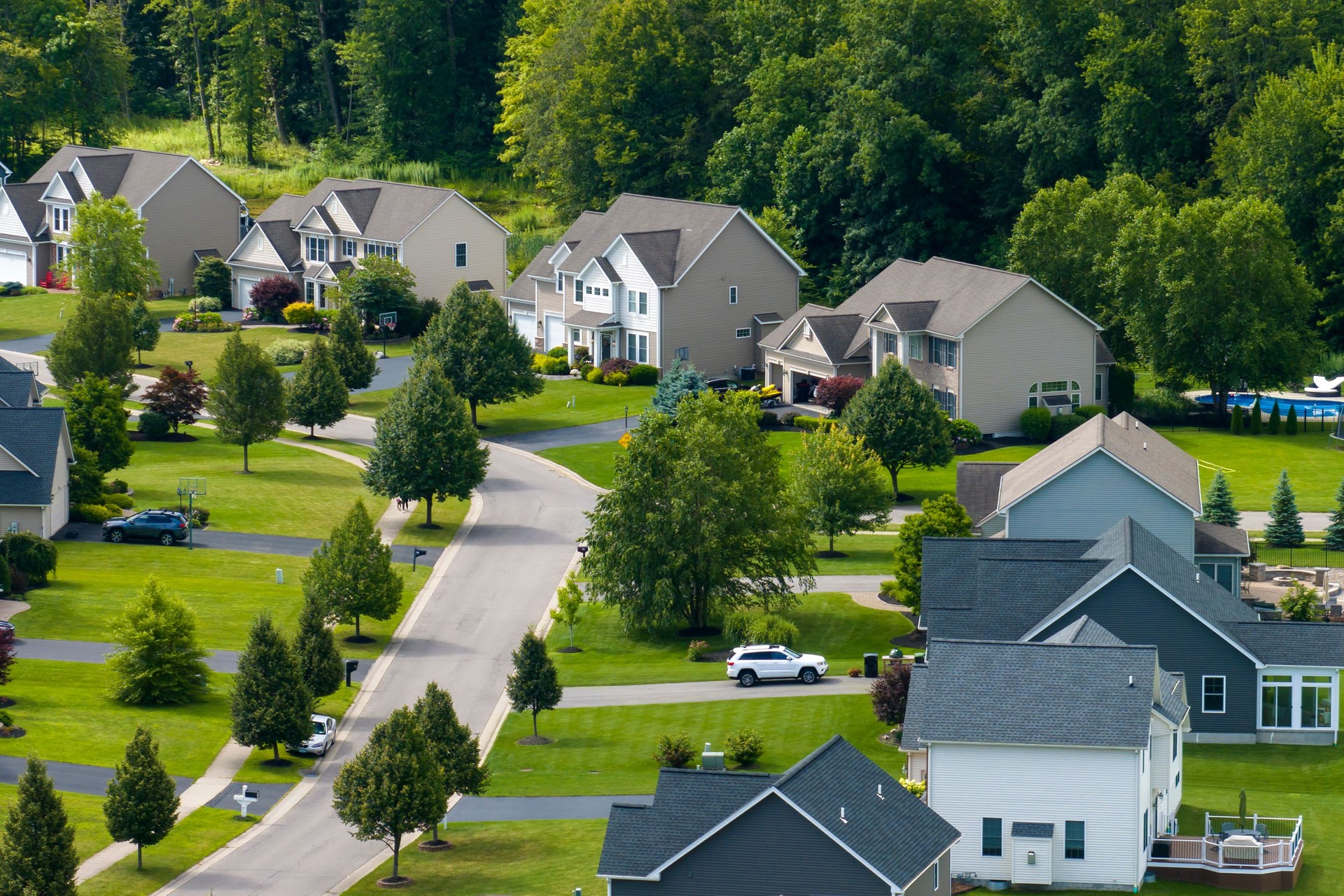 Aerial view of private residential houses in rural suburban sprawl area in Rochester, New York. Upscale suburban homes with large backyards and green grassy lawns in summer season